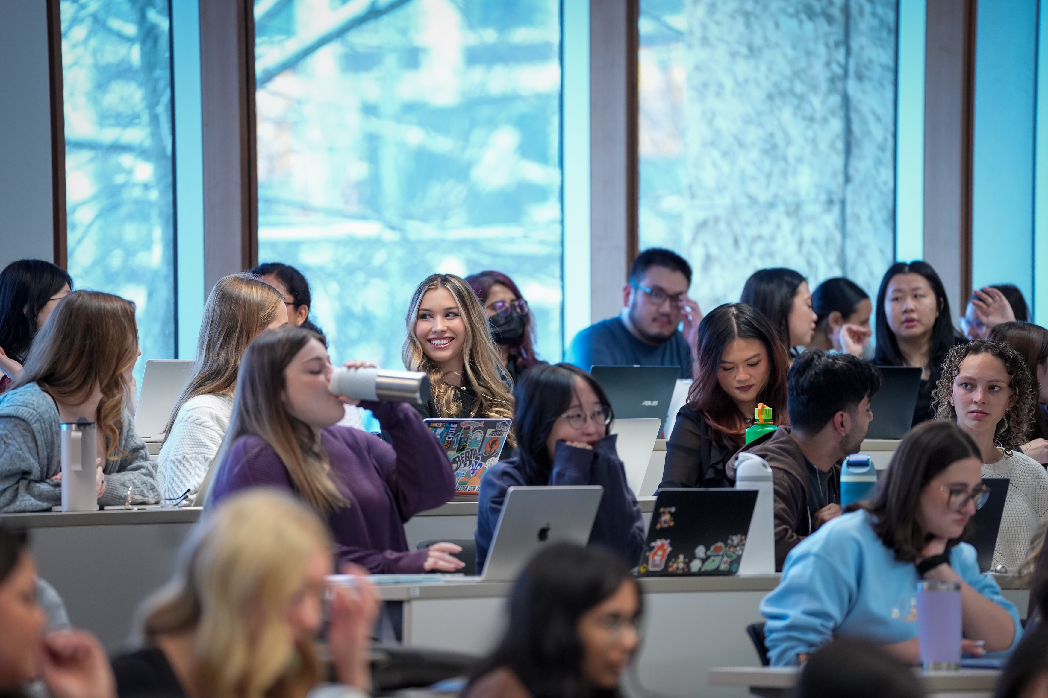 Students smiling in a classroom lecture hall