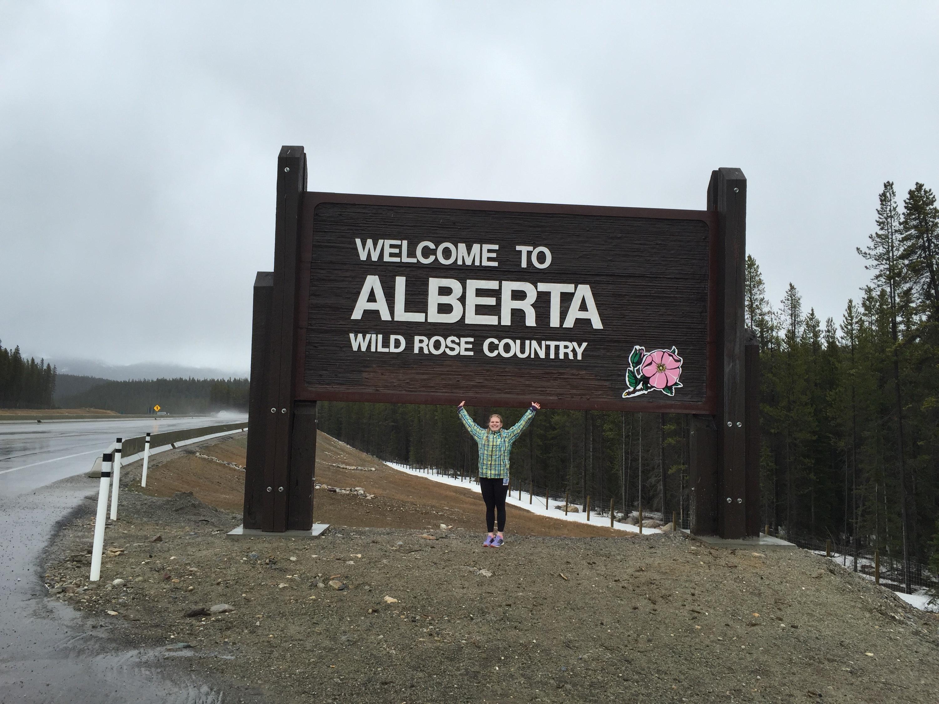 Sarah standing in front of welcome to Alberta sign