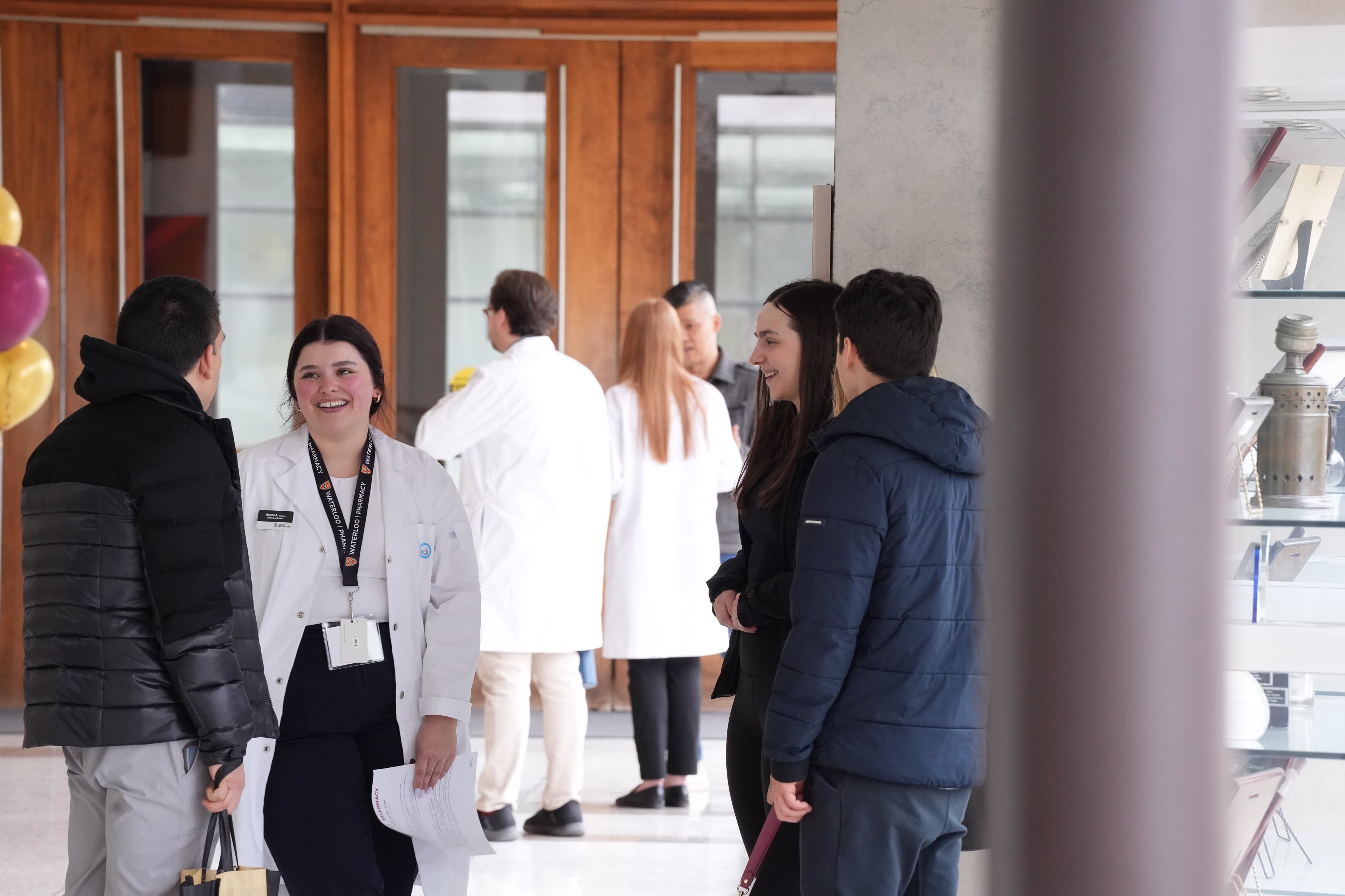 Student in white coat smiling as she talks to school visistors