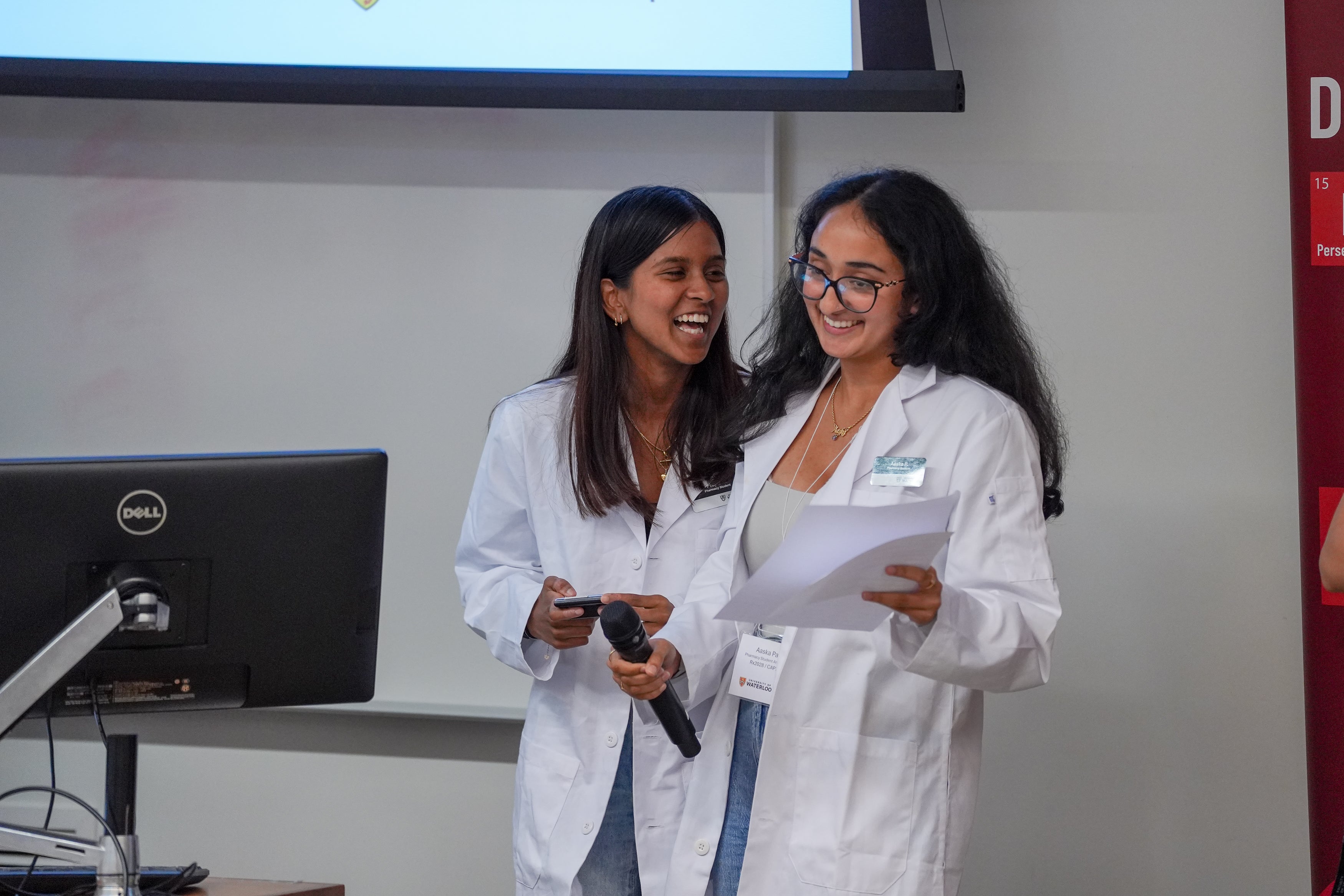 Two students smiling and laughing while presenting