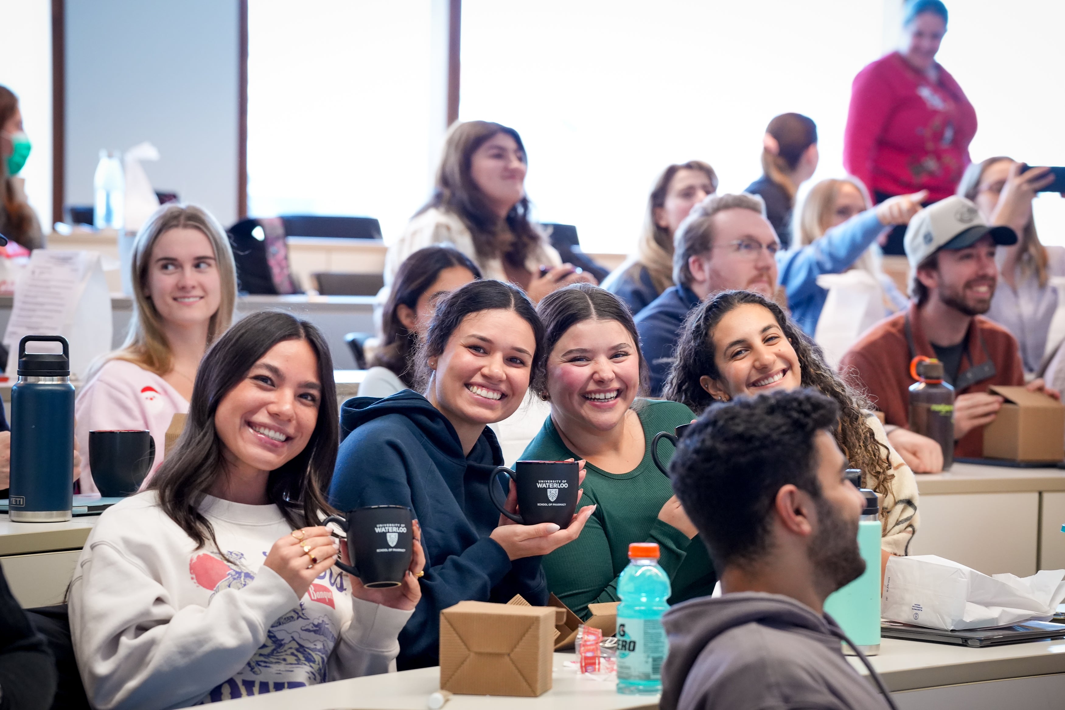 Students smiling holding up mugs