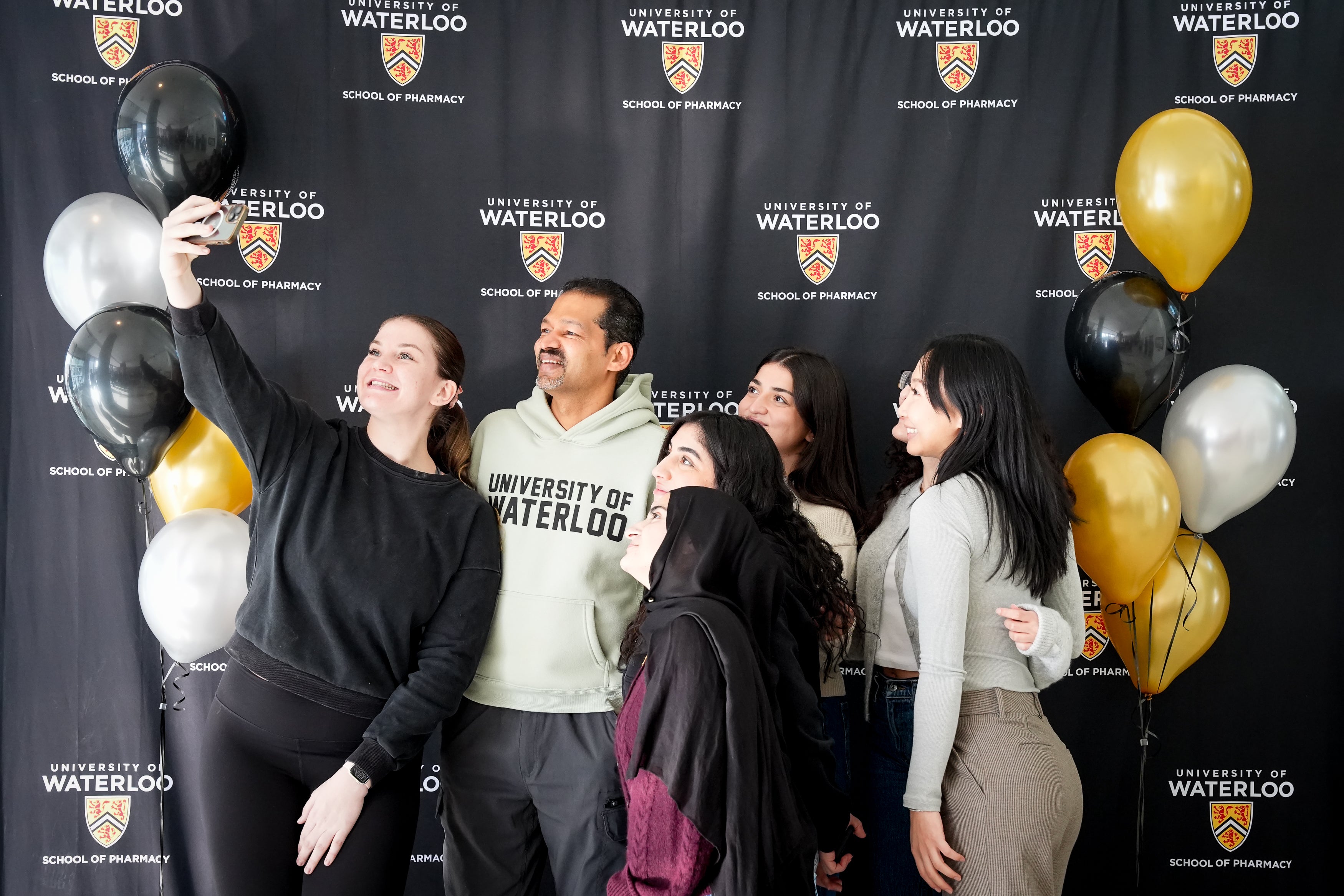Students taking a selfie with a professor in front of a banner