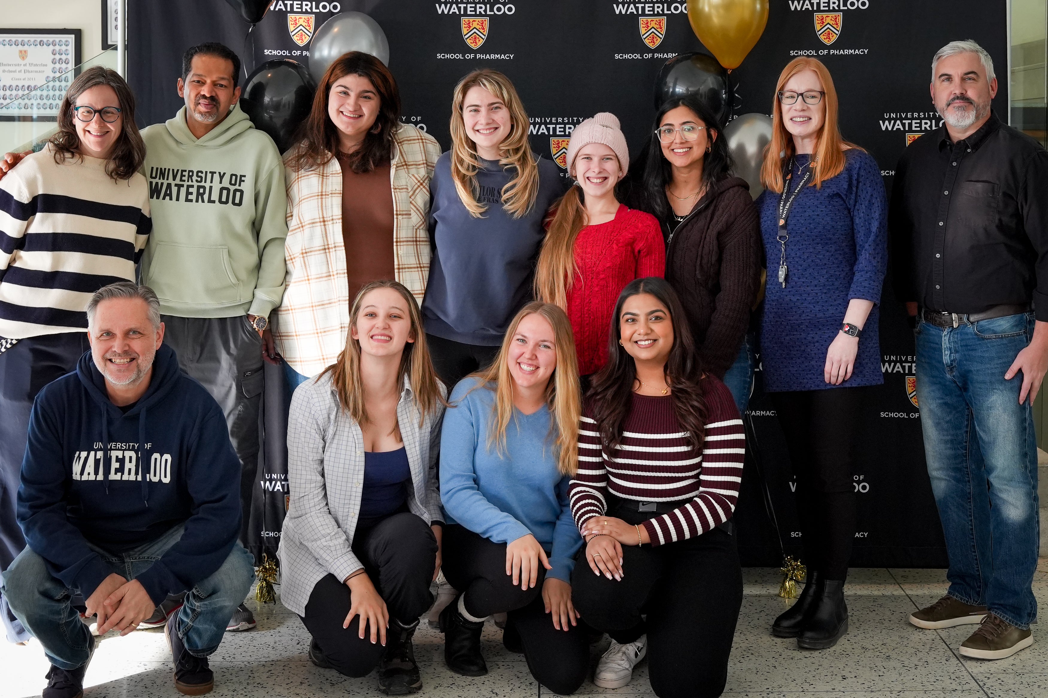 A group of students and professors smiling in front of a banner