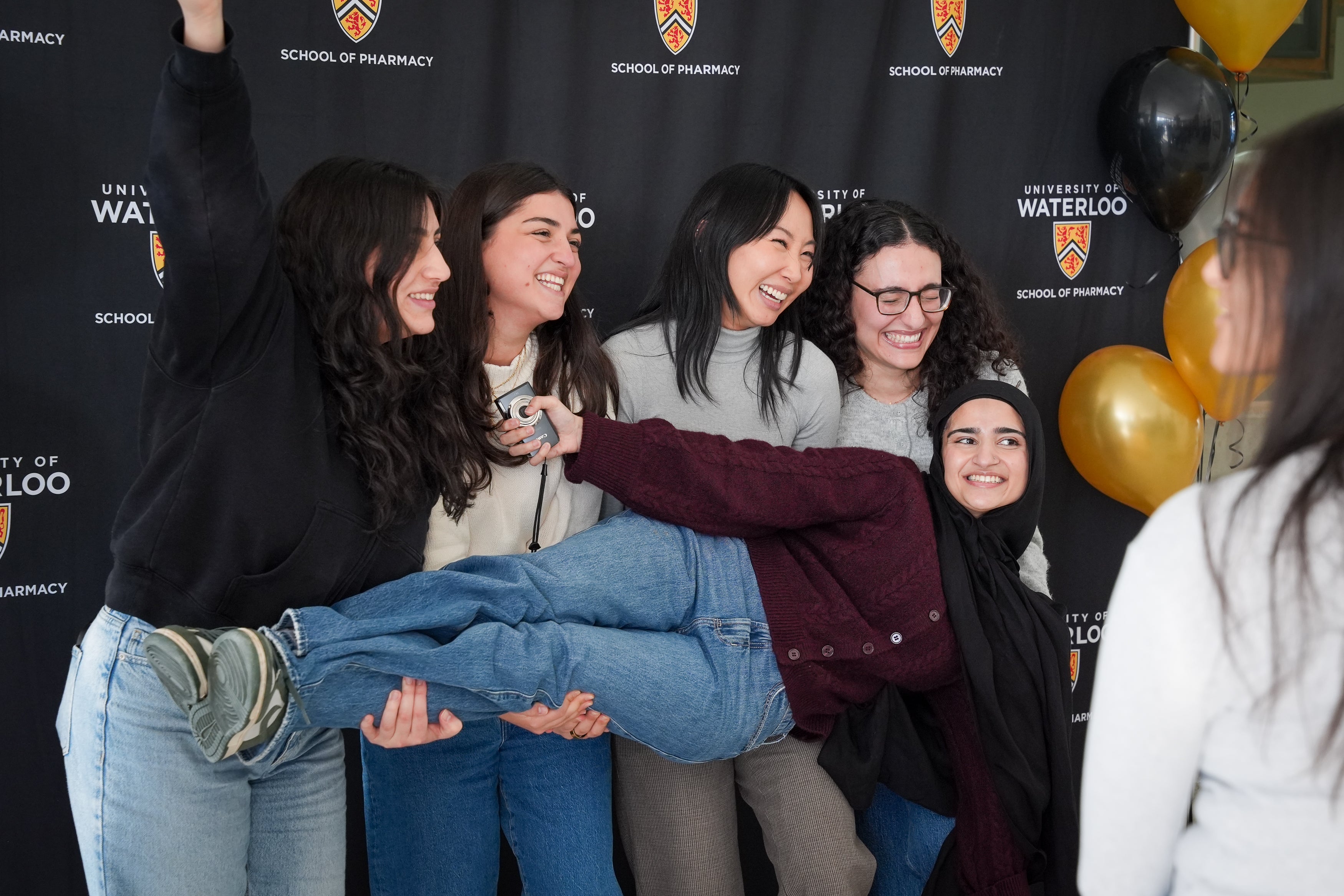 Students holding up another student in front of a banner