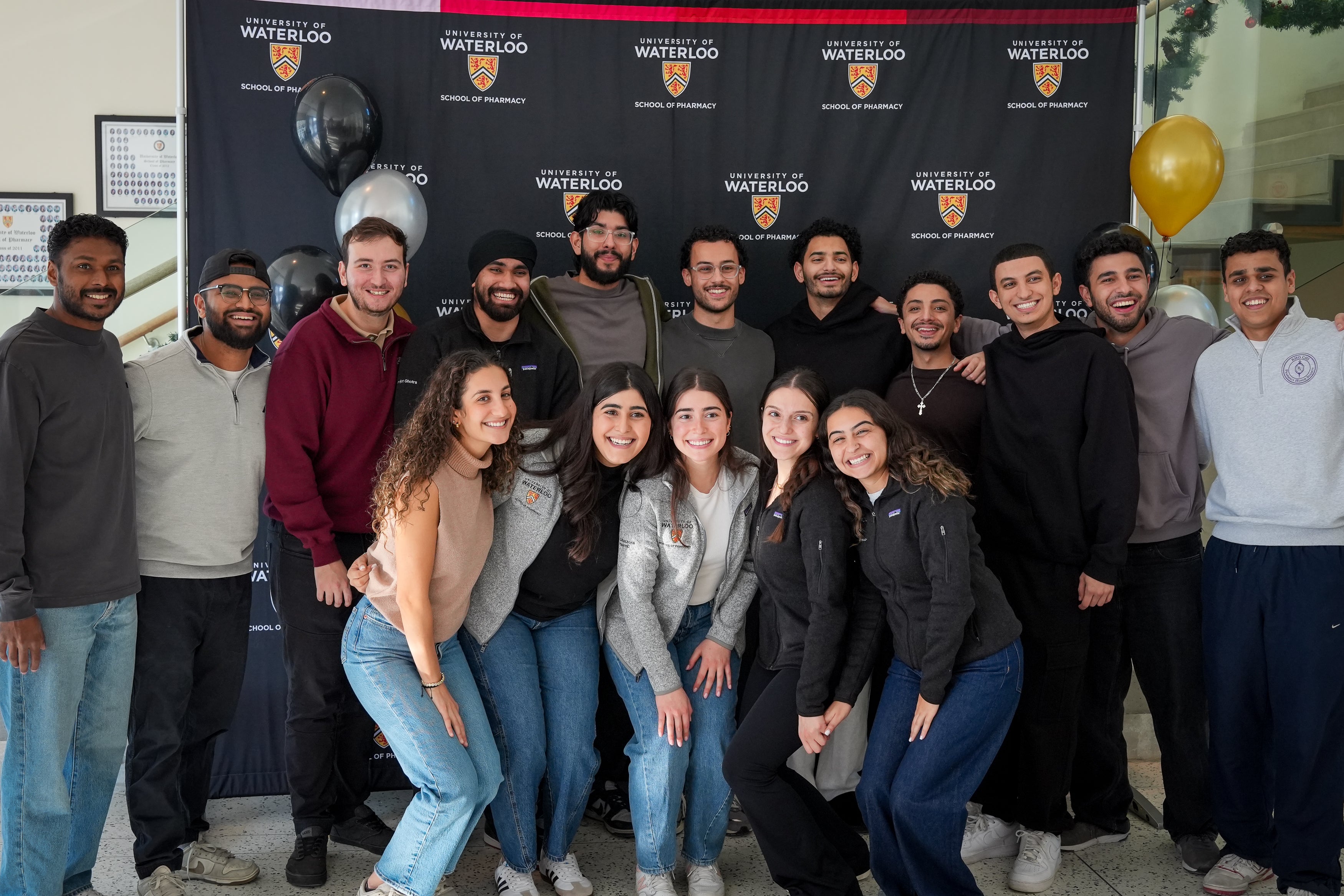 A group of students smiling in front of a banner