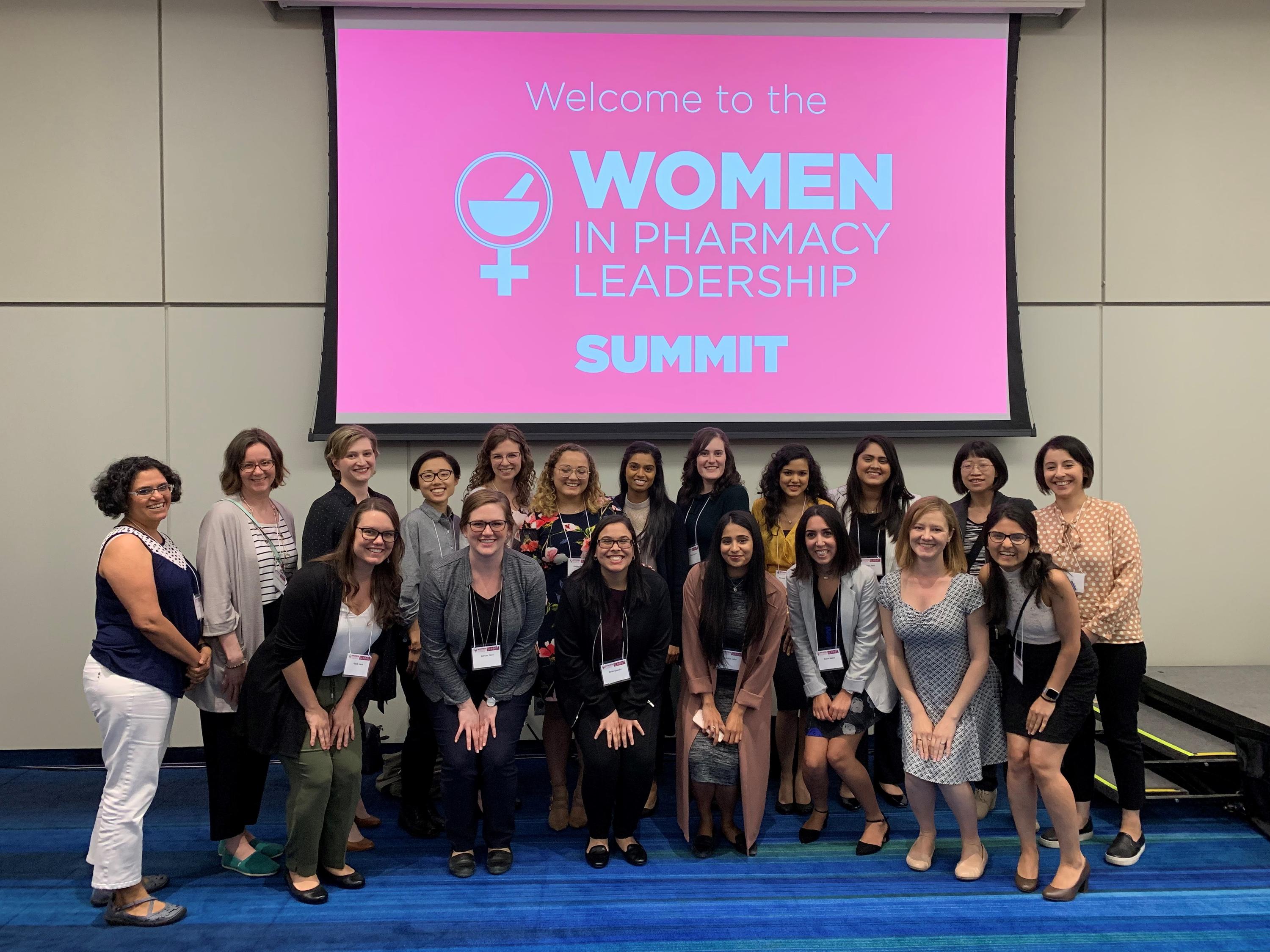 Waterloo Pharmacy faculty, alumni and students stand in front of a banner that says Women in Pharmacy Leadership Summit.