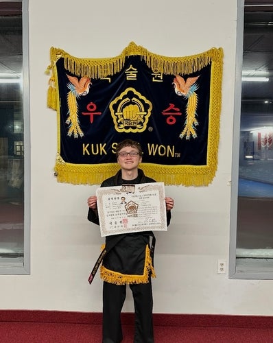 Luca Roy in a karate dojo holding a certificate