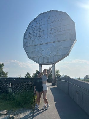 Two women standing in front of a big nickel monument in Sudbury, Ontario