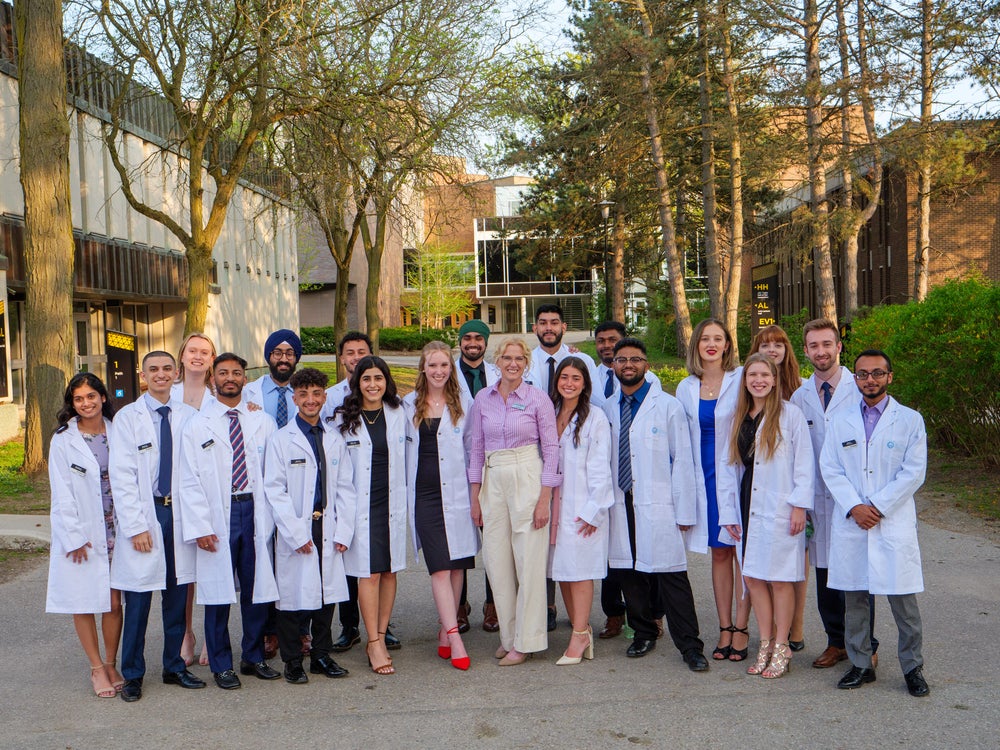 Andrea Edginton standing with a group of students in white coats