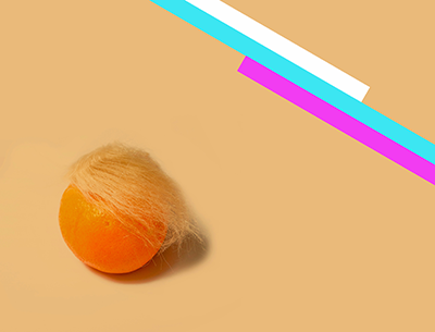 an orange with a blond wig on it and pink, blue and white stripes in back