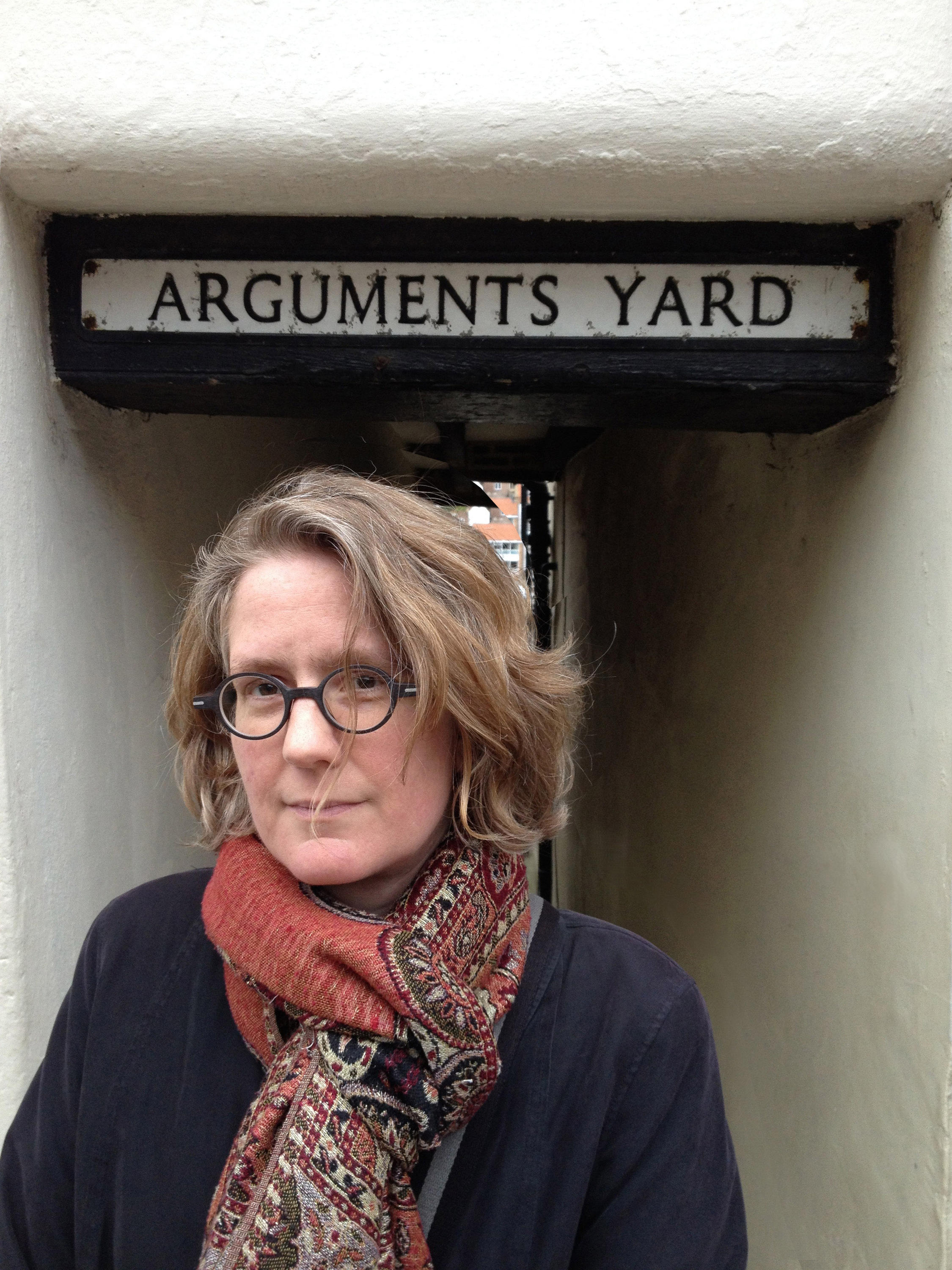 Dr. Jennifer Mather Saul in front of a sign reading Argument yard