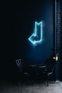 blue arrow- neon sign above table and chairs