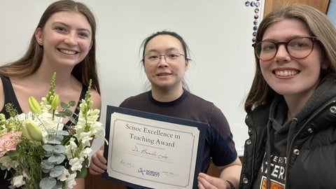 Brenda Lee with her teaching award and two of her students.