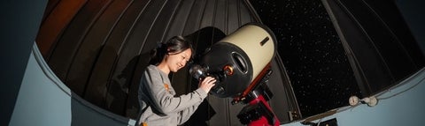 Student looking through telescope.