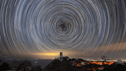 Long exposure of stars at night producing circular trails.