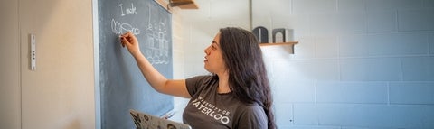 A graduate student writing on a chalk board.