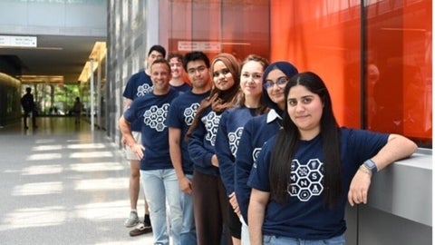 Members of MNS posing along a wall in the QNC building.