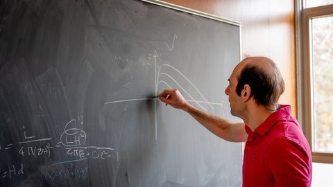 Niayesh Afshordi solving equations on a blackboard.