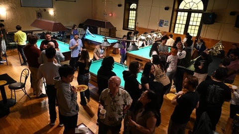 Students and faculty mingle around pool tables at the Huether Hotel