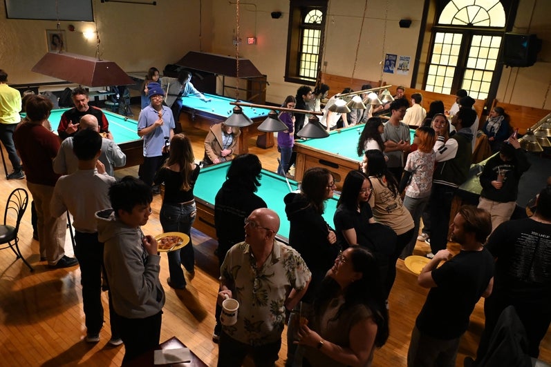 Students and faculty mingle around pool tables at the Huether Hotel