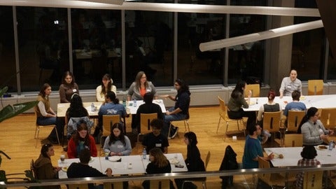 Mentoring night with groups of people talking while seated at tables.