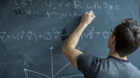 Person writing equations on a chalkboard.