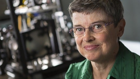 Dr. Melanie Campbell sits in her lab with optical equipment behind her