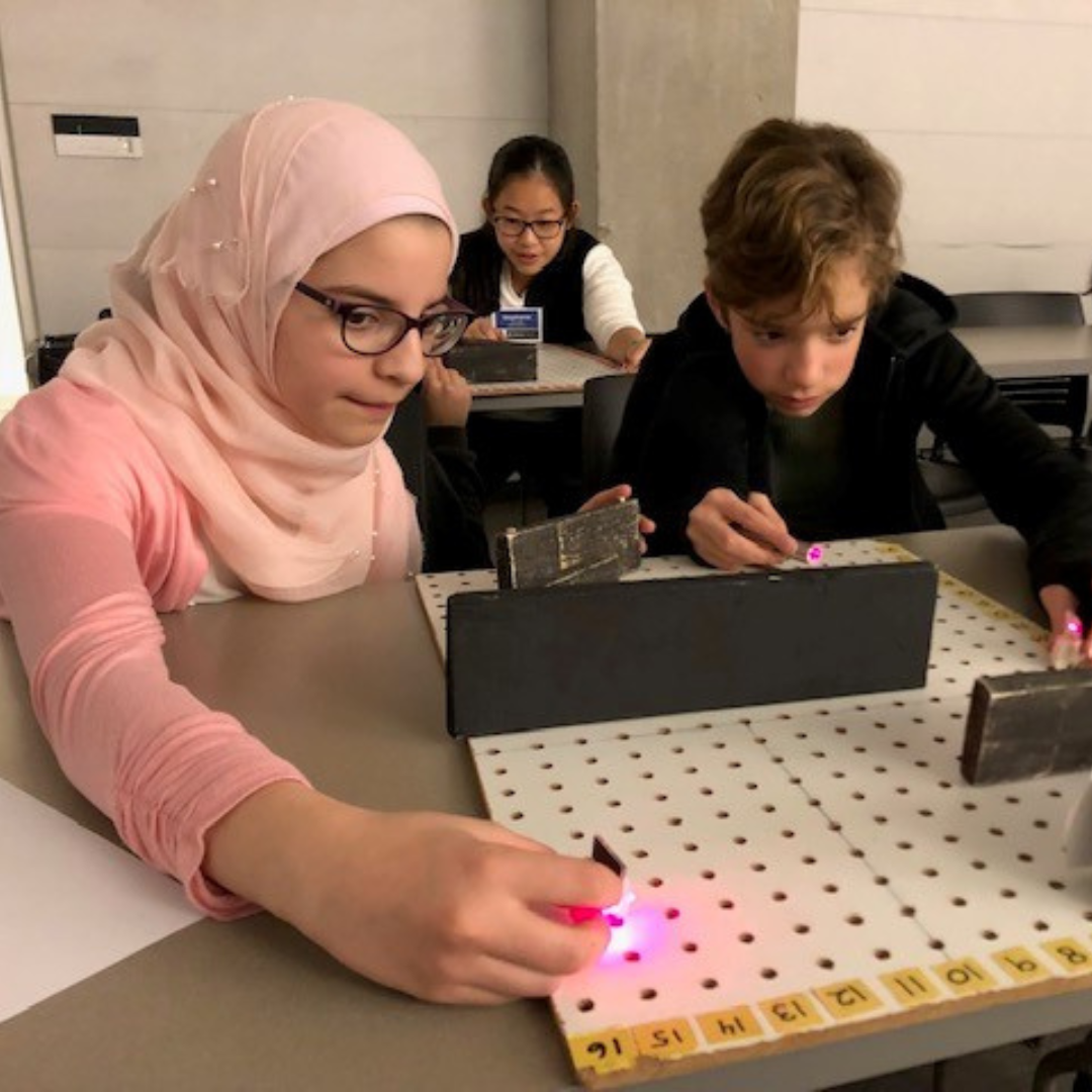 Bushra volunteering with kids on a physics experiment.