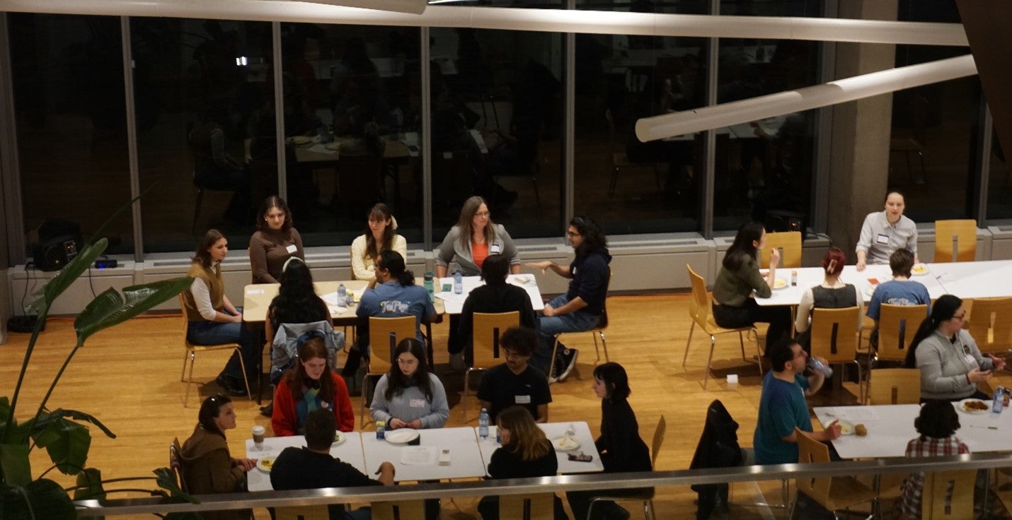 Mentoring night with groups of people talking while sitting at tables.