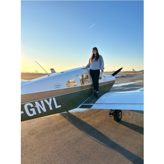 Chloe Muhl standing by a plane