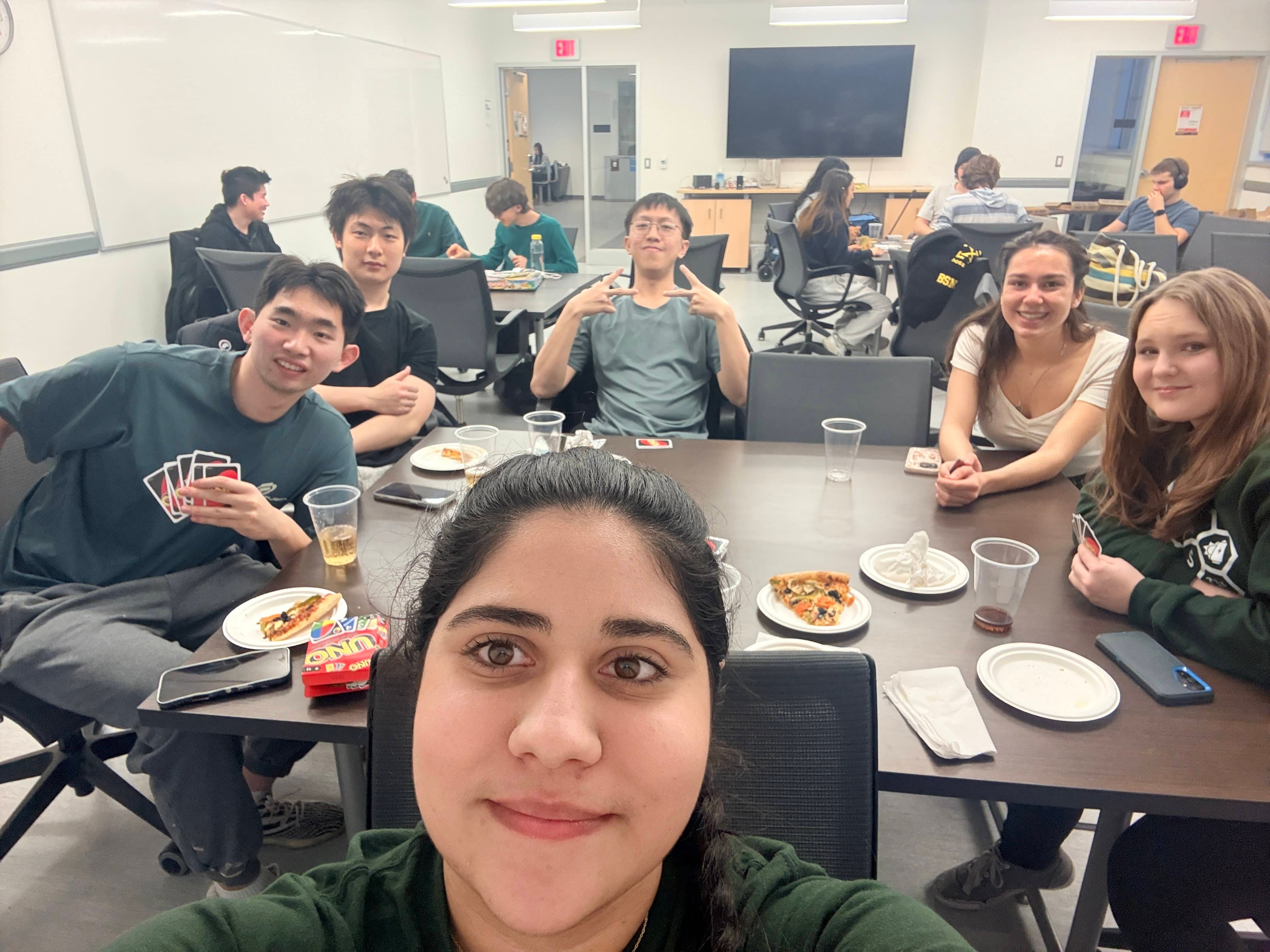 MNS games night with members playing cards and other games while eating pizza together.