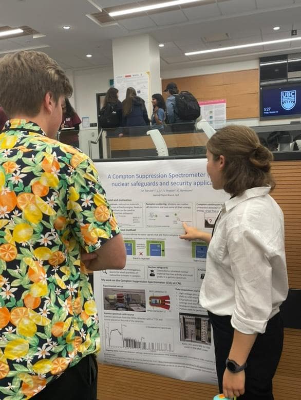 A student explaining their poster to another researcher at the CUPC