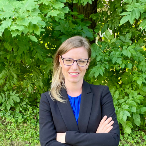 Headshot of School of Planning faculty member Jennifer Dean against a background of dense foliage.