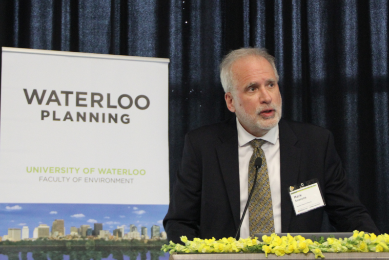 School of Planning Director Mark Seasons speaking in front of a podium and School of Planning banner