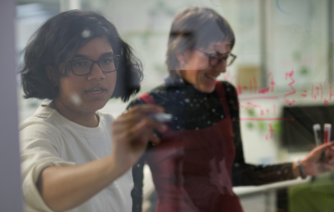 Two people writing equations