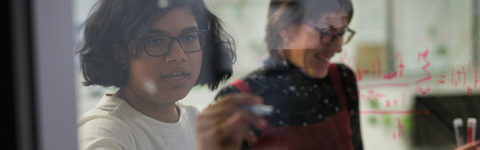 Two people writing equations