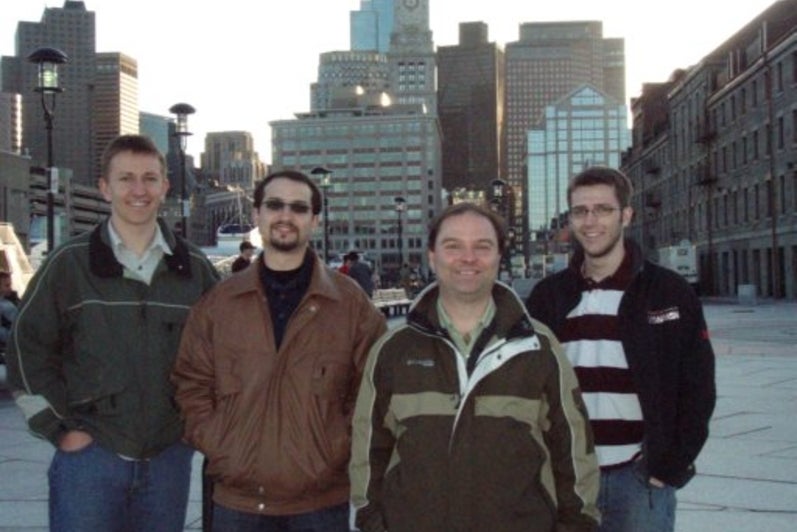 ASPE Topical Meeting (Boston), April 2010. Four men standing in front of Boston skyline.