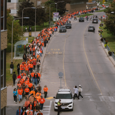 A long line of people on Ring Rd wearing orange shirts