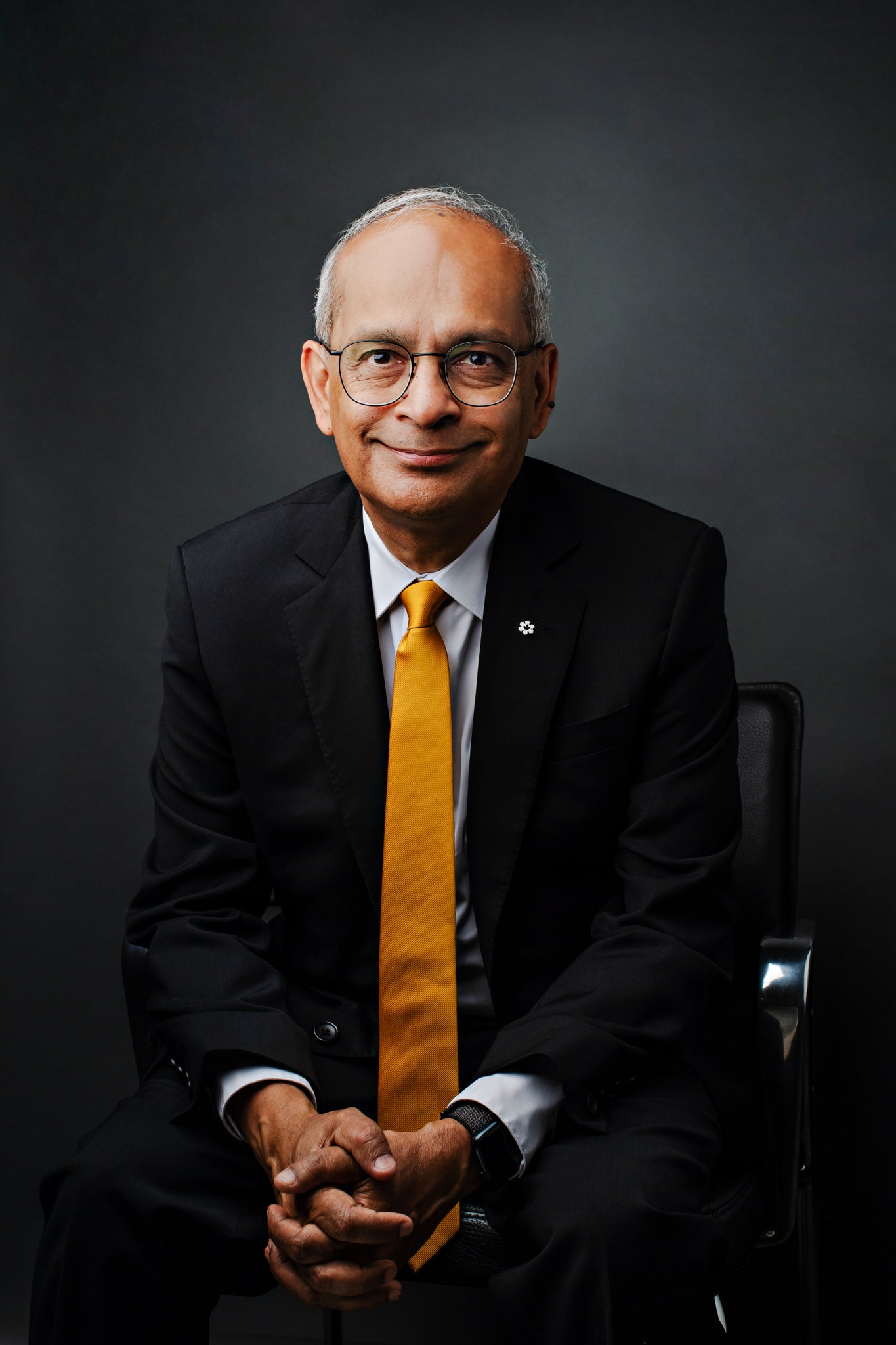 Vivek Goel seated with hands together smiling at camera