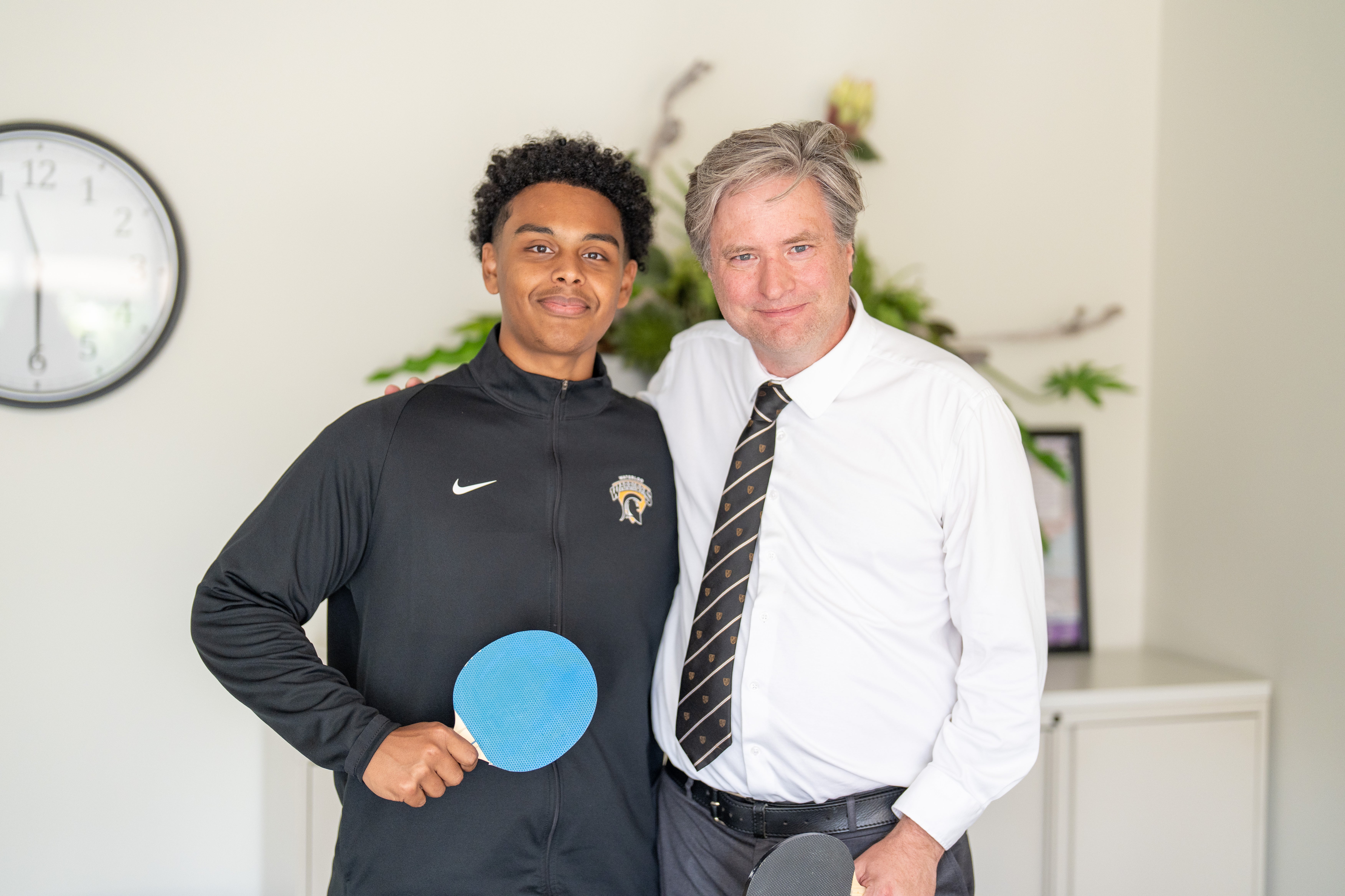 Bill standing with a student holding a ping pong paddle 