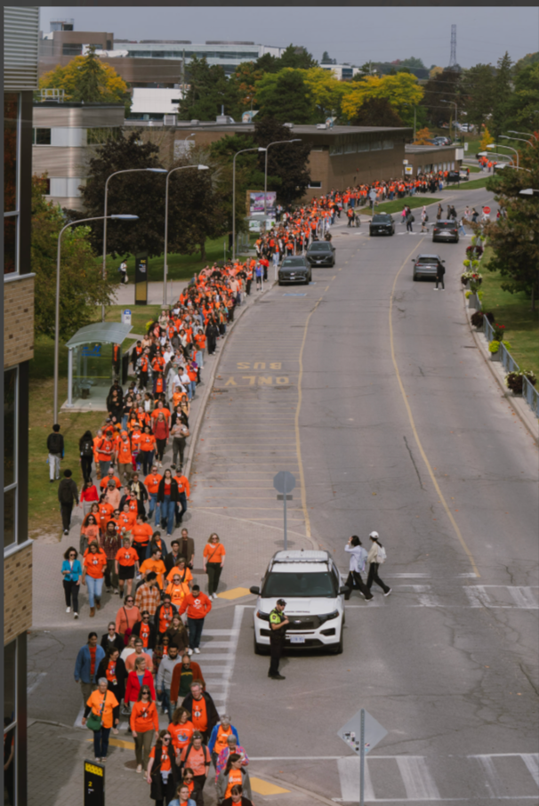 A long line of people on Ring Rd wearing orange shirts