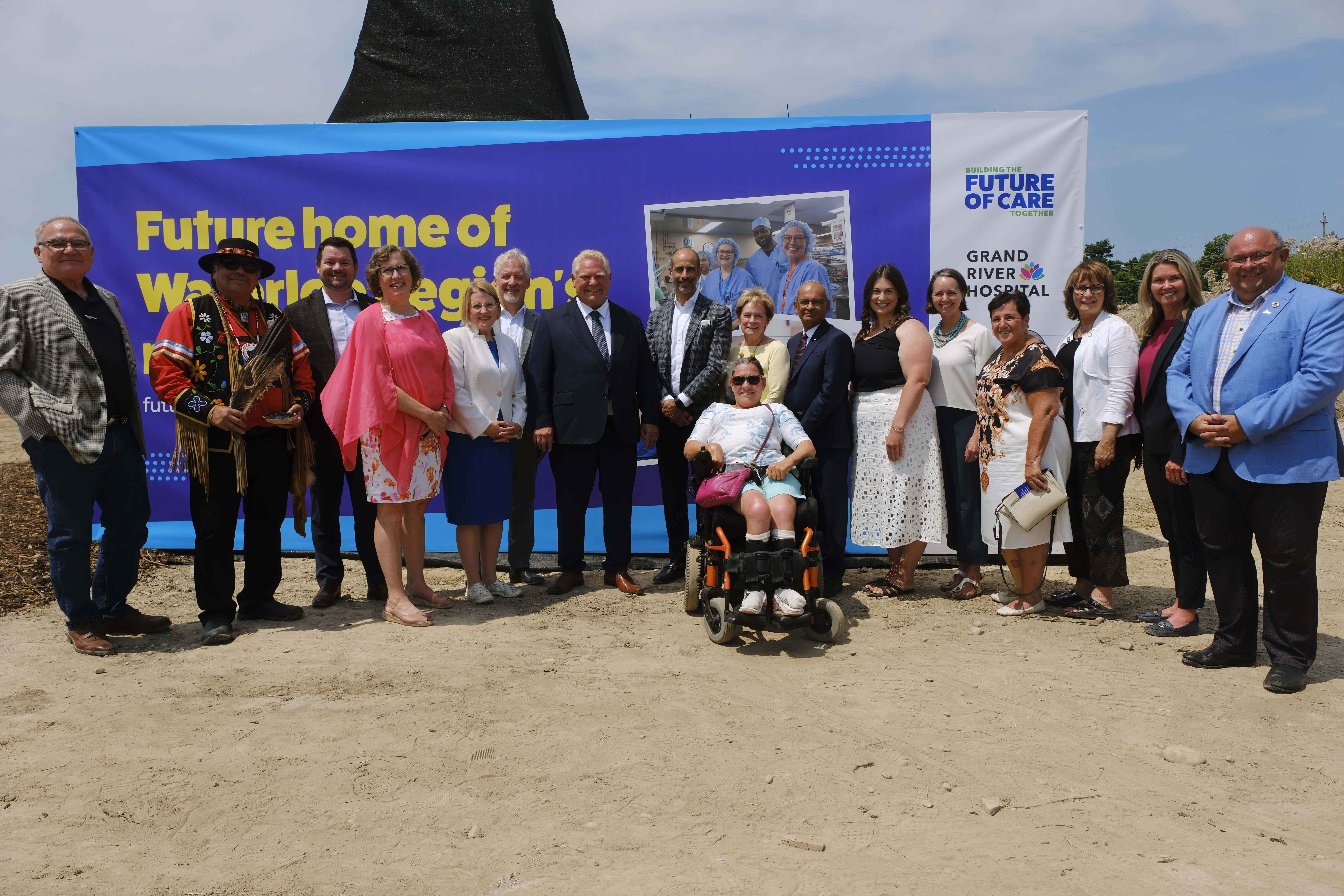 Hospital boards pose for group photo in front of sign announcing new hospital site