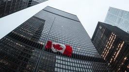Low-angle photo of skyscrapers with Canadian flag in foreground