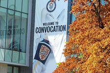 Welcome to convocation sign hangs on SLC Building with fall colours on display in foreground with orange leaves on a tree