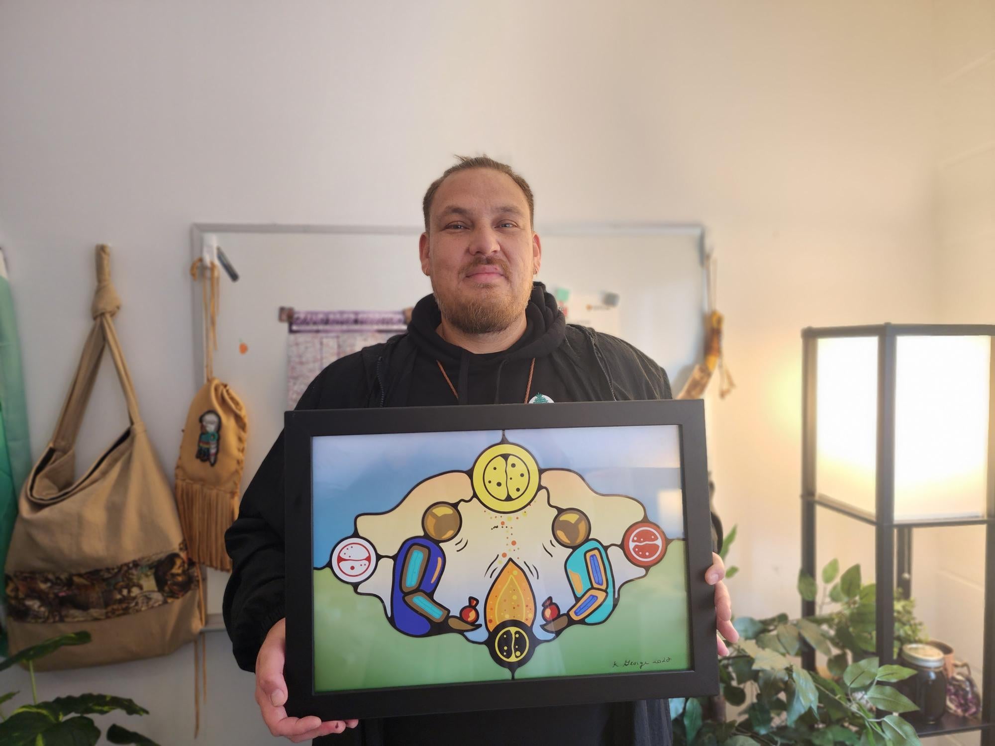 Kevin George holding up an Indigenous art piece