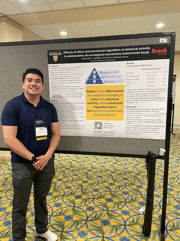Ryan Chen, smiling, standing in a conference hall in front of a research poster. Details provided in caption.