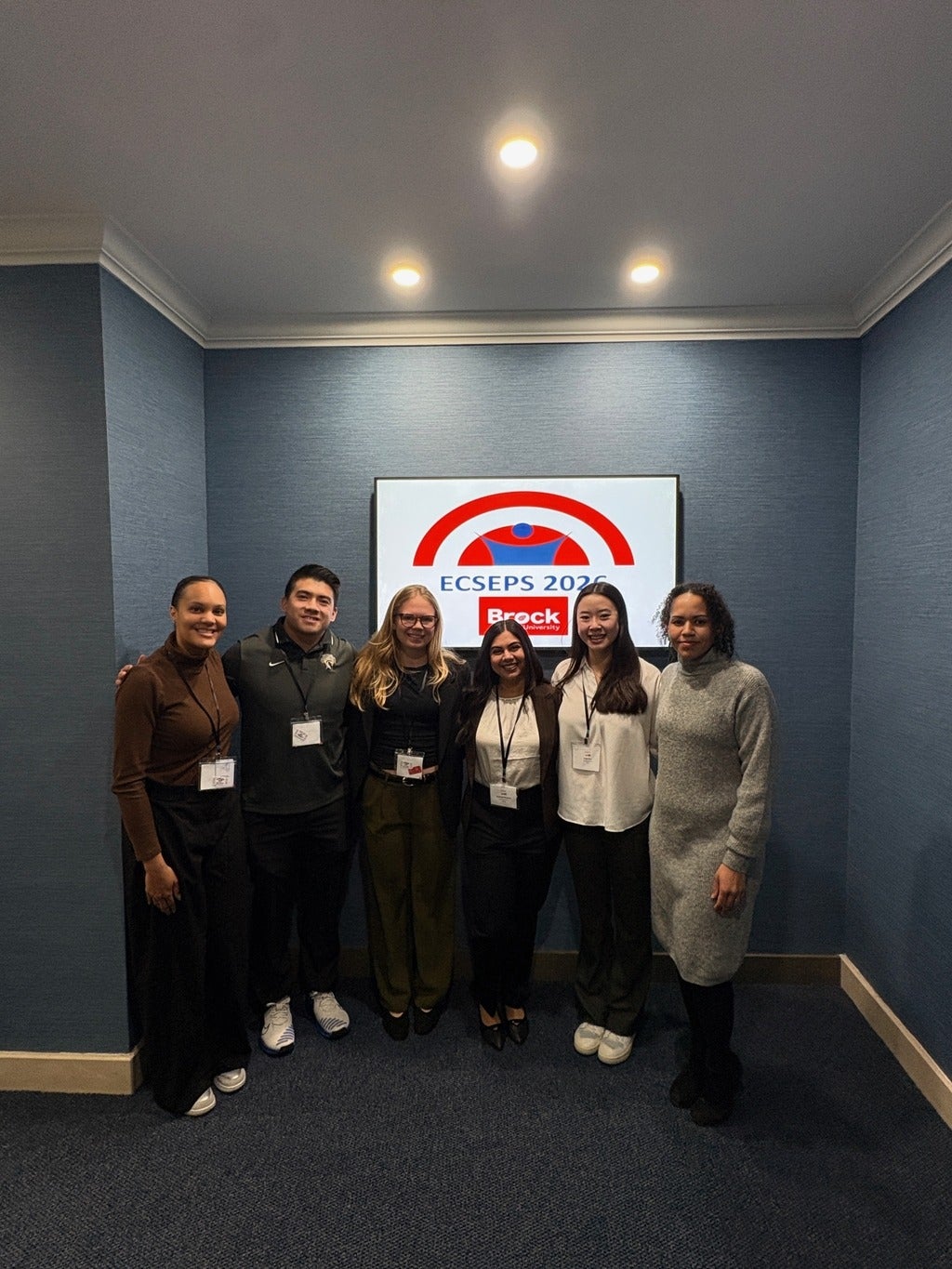 Group photo of PHRESH Lab and RISE Lab members standing in front of screen with ECSEPS Logo. From left to right: Dr. Sheereen Harris, Ryan Chen, Hannah Johnson, Sucheta Khurana, Kelly Dao, and Dr. Kaleigh Pennock.
