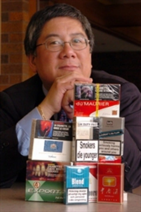 Geoffrey Fong behind stacks of cigarette packages