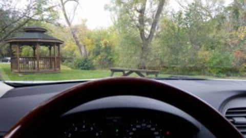 sitting in the car, behind the wheel, looking out at a gazebo in the park