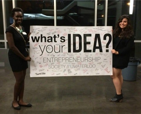 Two women holding up large "What's your Idea sign" 
